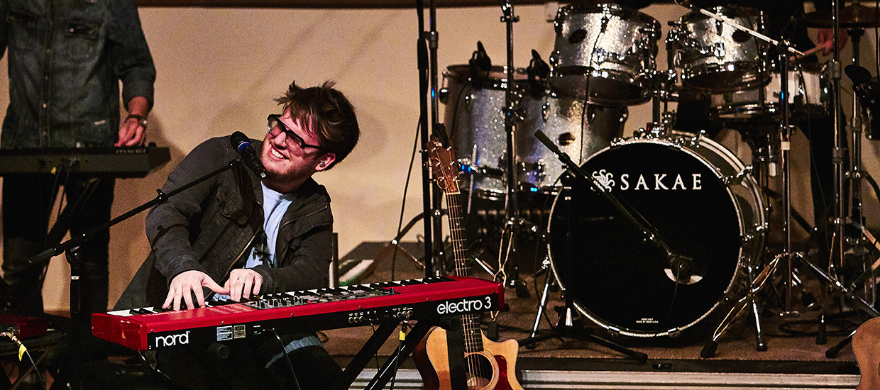 Man playing the keyboard while smiling on stage